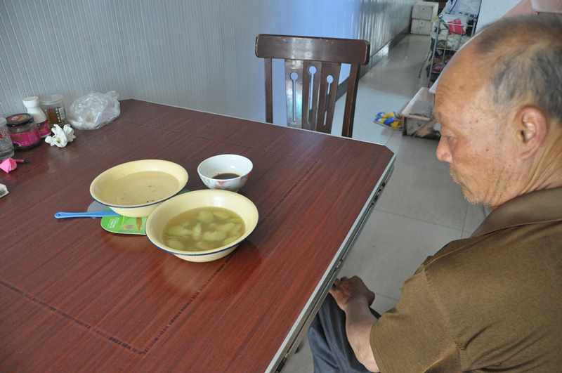 梁世磊的爷爷看着饭桌，桌上是一家人的中午吃的菜_副本.jpg